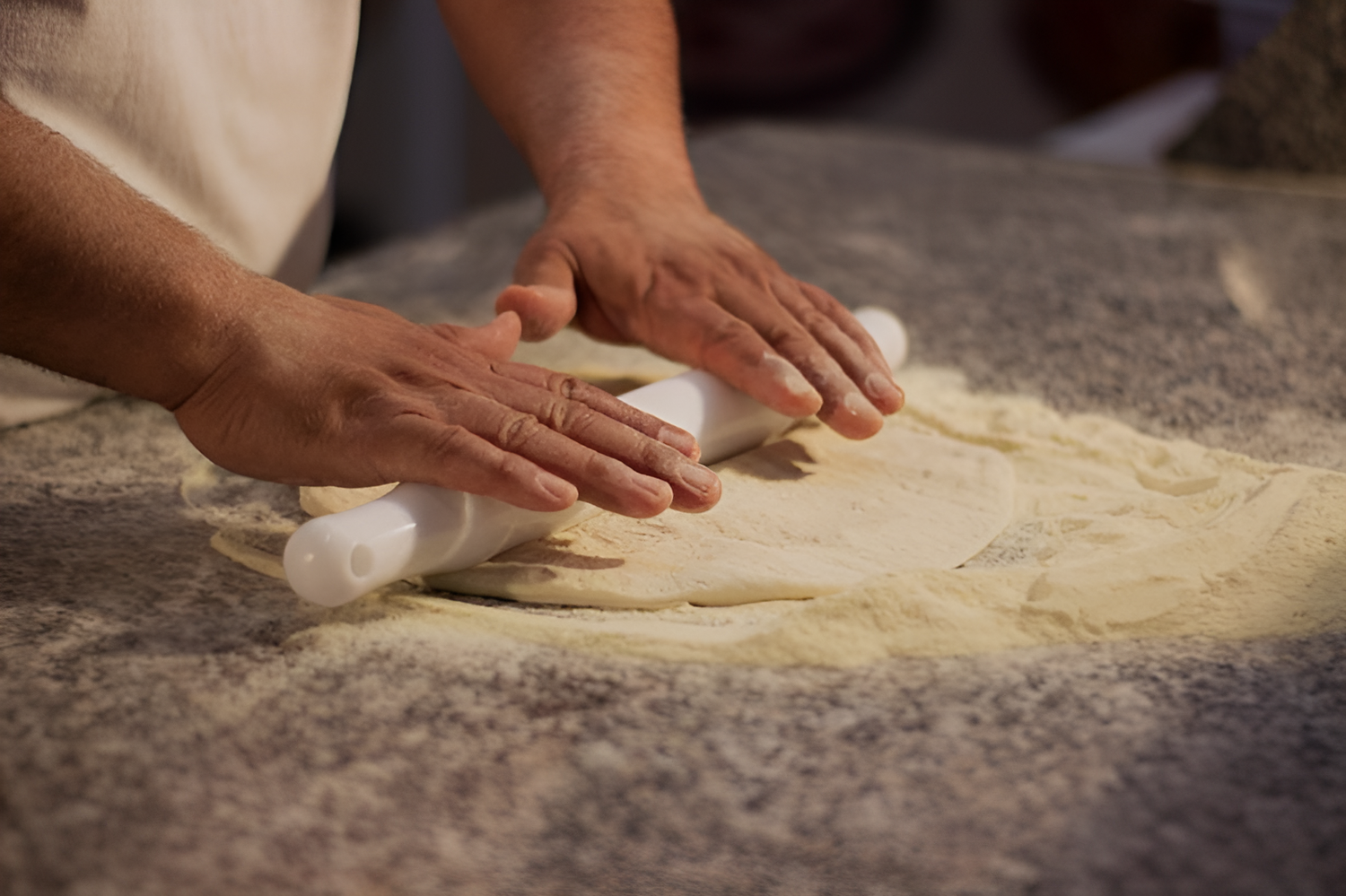 Person rolling dough on a stone surface